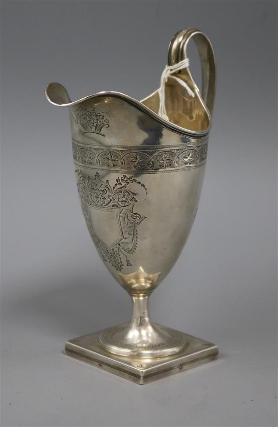 An antique white metal helmet shaped cream jug, on square foot, 19.3cm.